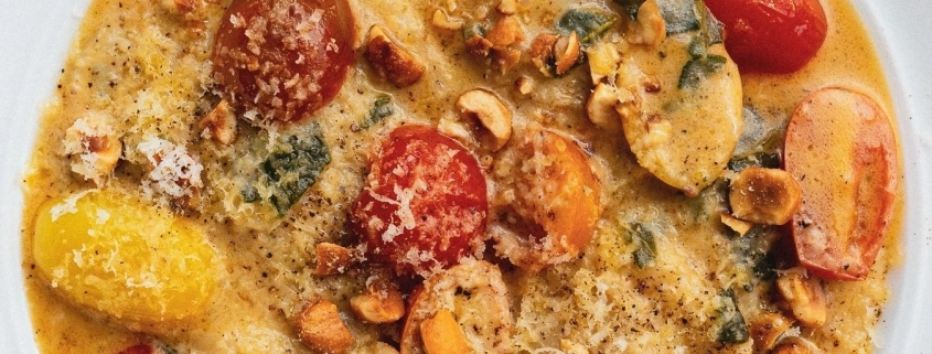 Creamy butternut squash ravioli served at a vegan restaurant Midtown NYC with roasted cherry tomatoes and hazelnuts.